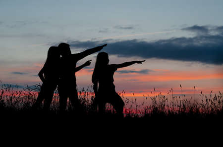 three silhouettes at sunset show direction beautiful skyのeditorial素材