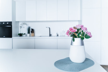 In a white kitchen, a vase of pink roses sits on a worktop. Concept interior, space, inspirationの写真素材