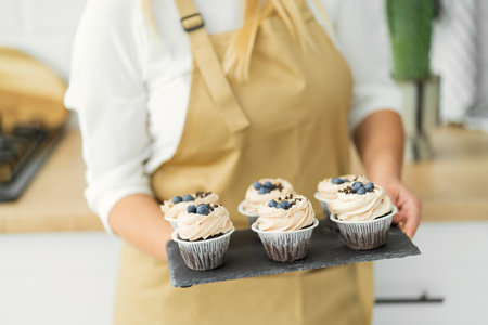 A woman holds a bowl of fresh blueberries in her hands. close up concept confectioner, nutritionist,...