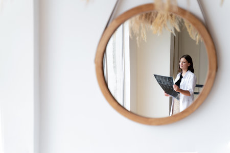A woman doctor in a white coat takes an X-ray picture of a patient. Concept mirror, abstraction,...