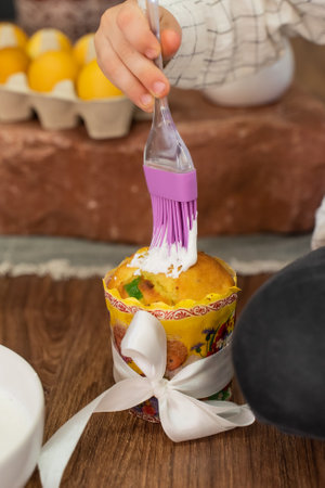 A boy brushes Easter cake with egg white in the kitchen.の写真素材