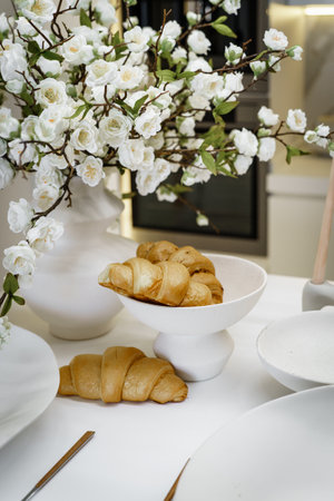 Stylish breakfast with croissants in a white kitchen with flowersの写真素材