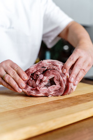 Twisted raw meat ribs on a wooden board with spices and salt being preparedの写真素材