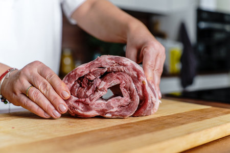 Woman rolls raw pork ribs at table, close-upの写真素材