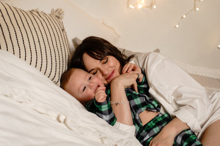 Motherly love. A mother hugs her son in bed.の写真素材