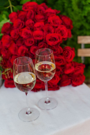 There are two glasses on the table and a bouquet of roses in the background. Valentines Dayの写真素材