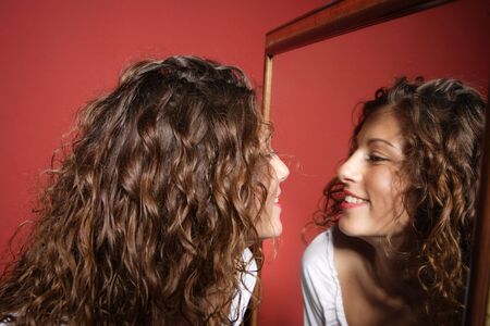 A beautiful sexy women  looking at her reflection in the miror on red background
の写真素材