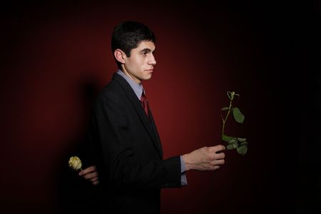 Young happy smiling handsome man with yellow rose, dark tone
の写真素材