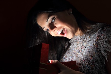 A beautiful young woman posing on red background with a gift in her hands

の写真素材