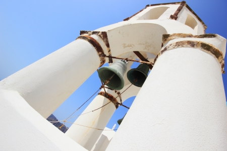 Traditional Greek white church arch with cross and bells in village Oia of Cyclades Island Santorini Greeceの写真素材