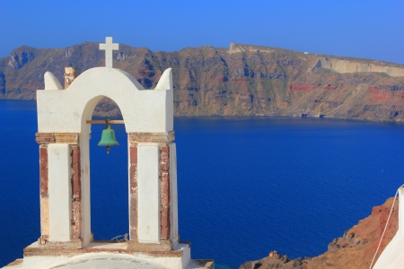 Traditional Greek white church arch with cross and bells in village Oia of Cyclades Island Santorini Greeceの写真素材