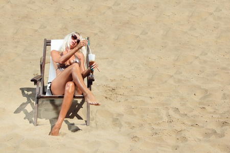 Young beautiful blond woman on a beach holding a coffee in her handの写真素材