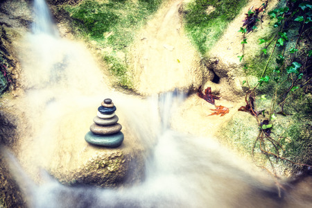 Balanced Rock Zen Stack in front of waterfall.の写真素材