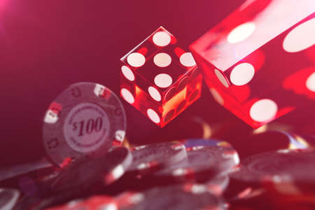Rolling red dices and Casino chips on a gaming table