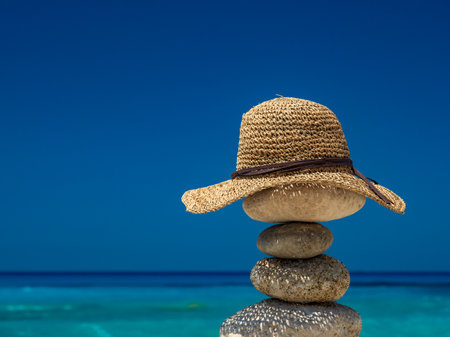 Straw Sunhat at the beach on balanced stonesの写真素材