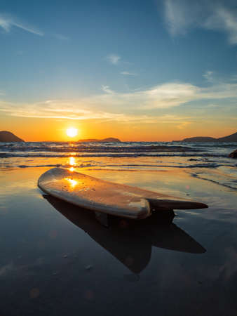 Surfboard on the beach at sunsetの写真素材