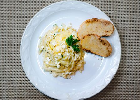 3 cheese pasta in white plate with garlic bread