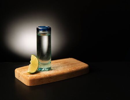 tequila shot with lemon on black background