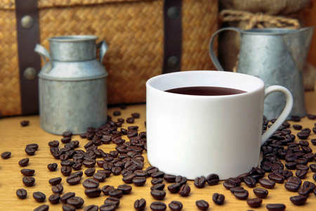 Hot coffee with coffee bean on wooden table and zinc pots, hamper basket and sack background