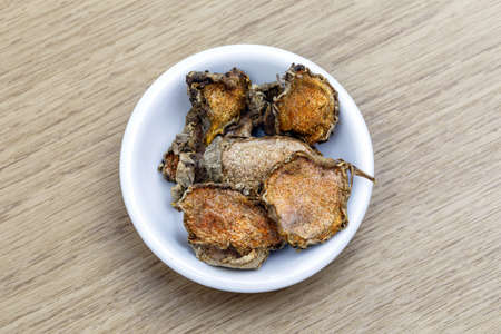 Dry turmeric in white bowl on wooden tableの写真素材