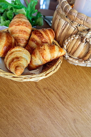 Croissant in basket on woodend table for breakfastの写真素材