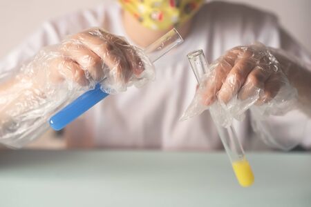 a child in a white t-shirt in the laboratory is studying chemistry . Young scientists in protective...
