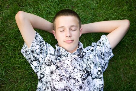 happy boy lying on grassの写真素材