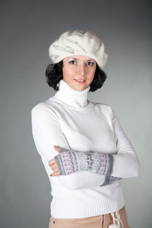 Beautiful young woman wearing wool sweater and winter hatover the grey background. の写真素材