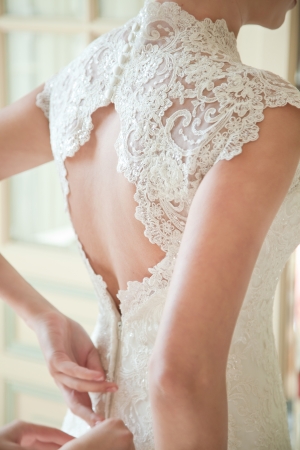 Bride putting on her white wedding dress