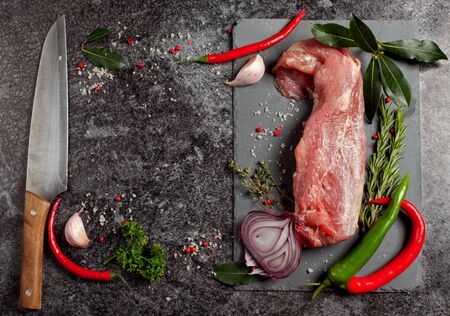Raw fresh meat and seasoning on black slate board background ready for roastingの写真素材