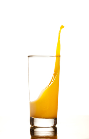 Orange juice or cocktail splashes out of the glass isolated on white backgroundの写真素材
