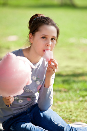 Young girl eating cotton candy in the parkの写真素材