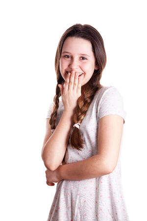 Young teenager girl giggling with her arm in front of mouth over the white backgroundの写真素材
