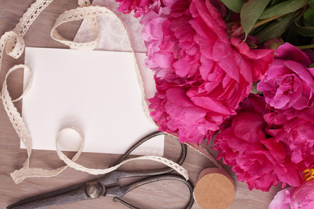 Flat lay of empty card and bouquet of peonies with copy space. Concept of love, greetings, invitation. top viewの写真素材