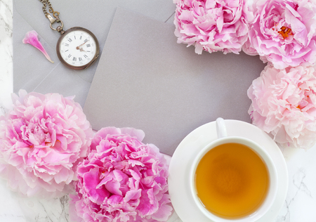 Flat lay over light background with peonies and cup of tea.の写真素材