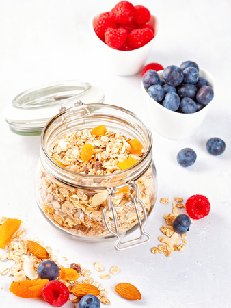 Jar with homemade granola or oatmeal muesli with nuts, dried fruits and fresh berries. Healty diet breakfast, vegan or vegeterian food conceptの写真素材