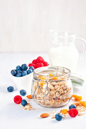 Jar with homemade granola or oatmeal muesli with nuts, dried fruits and fresh berries. Healty diet breakfast, vegan or vegeterian food conceptの写真素材
