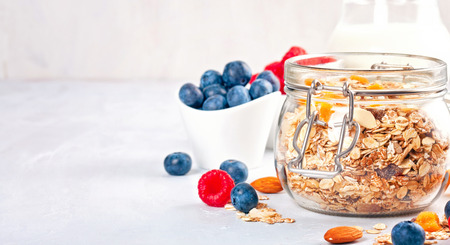 Jar with homemade granola or oatmeal muesli with nuts, dried fruits and fresh berries. Healty diet breakfast, vegan or vegeterian food conceptの写真素材
