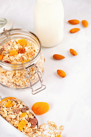 Jar with homemade granola or oatmeal muesli with nuts and dried fruits and almond milk. Healty diet breakfast, vegan or vegeterian food conceptの写真素材