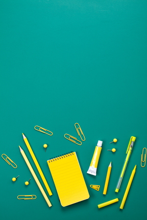 Yellow school supplies over the green board. Education, studing and back to school conceptの写真素材