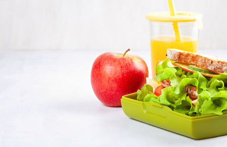 Fresh sandwich, apple and orange juice for healthy lunch of a kid or a student in the plastic lunch boxの写真素材