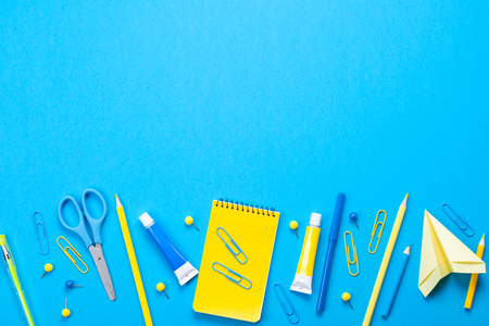 Yellow school supplies over the blue pastel background. Education, studing and back to school conceptの写真素材