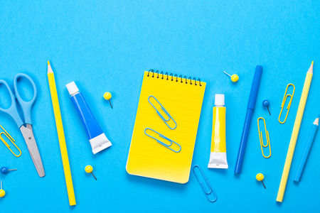 Yellow school supplies over the blue pastel background. Education, studing and back to school conceptの写真素材