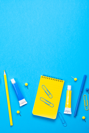 Yellow school supplies over the blue pastel background. Education, studing and back to school conceptの写真素材