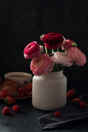 Romantic breakfast ith coffee, croissants and beautiful bouquet of flowers. Dark photoの写真素材