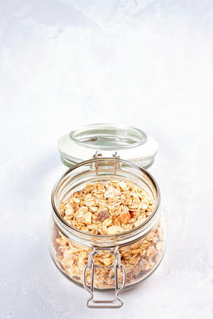 Jar with homemade granola or oatmeal muesli with nuts and dried fruits. Healty diet breakfast, vegan or vegeterian food conceptの写真素材