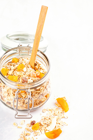 Jar with homemade granola or oatmeal muesli with nuts and dried fruits. Healty diet breakfast, vegan or vegeterian food conceptの写真素材