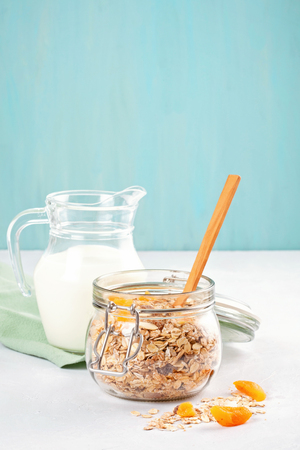 Jar with homemade granola or oatmeal muesli with nuts and dried fruits and milk. Healty diet breakfast, vegeterian food conceptの写真素材