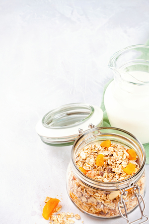Jar with homemade granola or oatmeal muesli with nuts and dried fruits and milk. Healty diet breakfast, vegeterian food conceptの写真素材