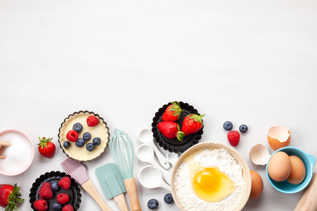 Baking utensils and cooking ingredients for tarts, cookies, dough and pastry. Flat lay with eggs, flour, sugar, berries.Top view, mockup for recipe, culinary classes, cooking blog.の写真素材